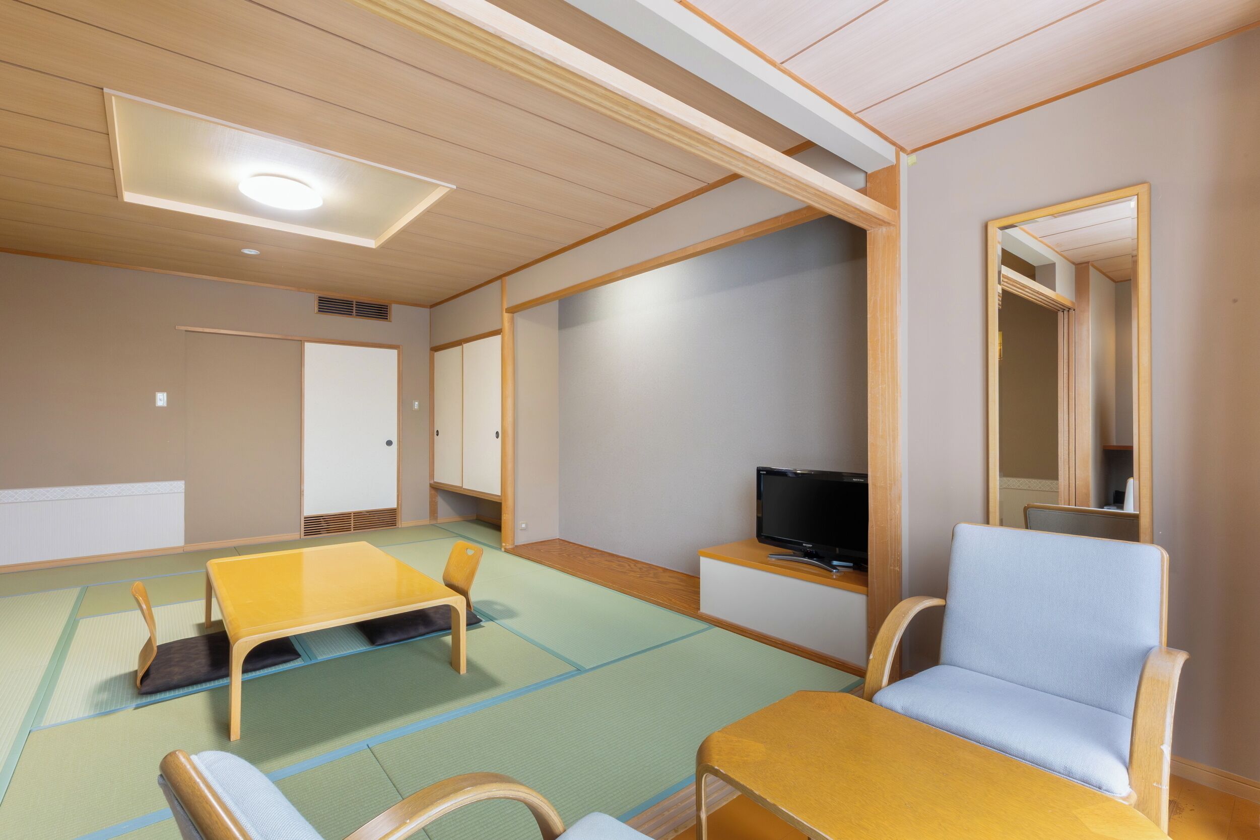 A room with tatami mats, a television, a sofa, and a cabinet.