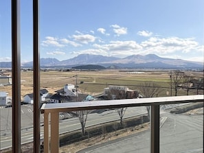 A view from a window overlooking a road with buildings and mountains in the distance. - Hotel Kadoman (Aso)
