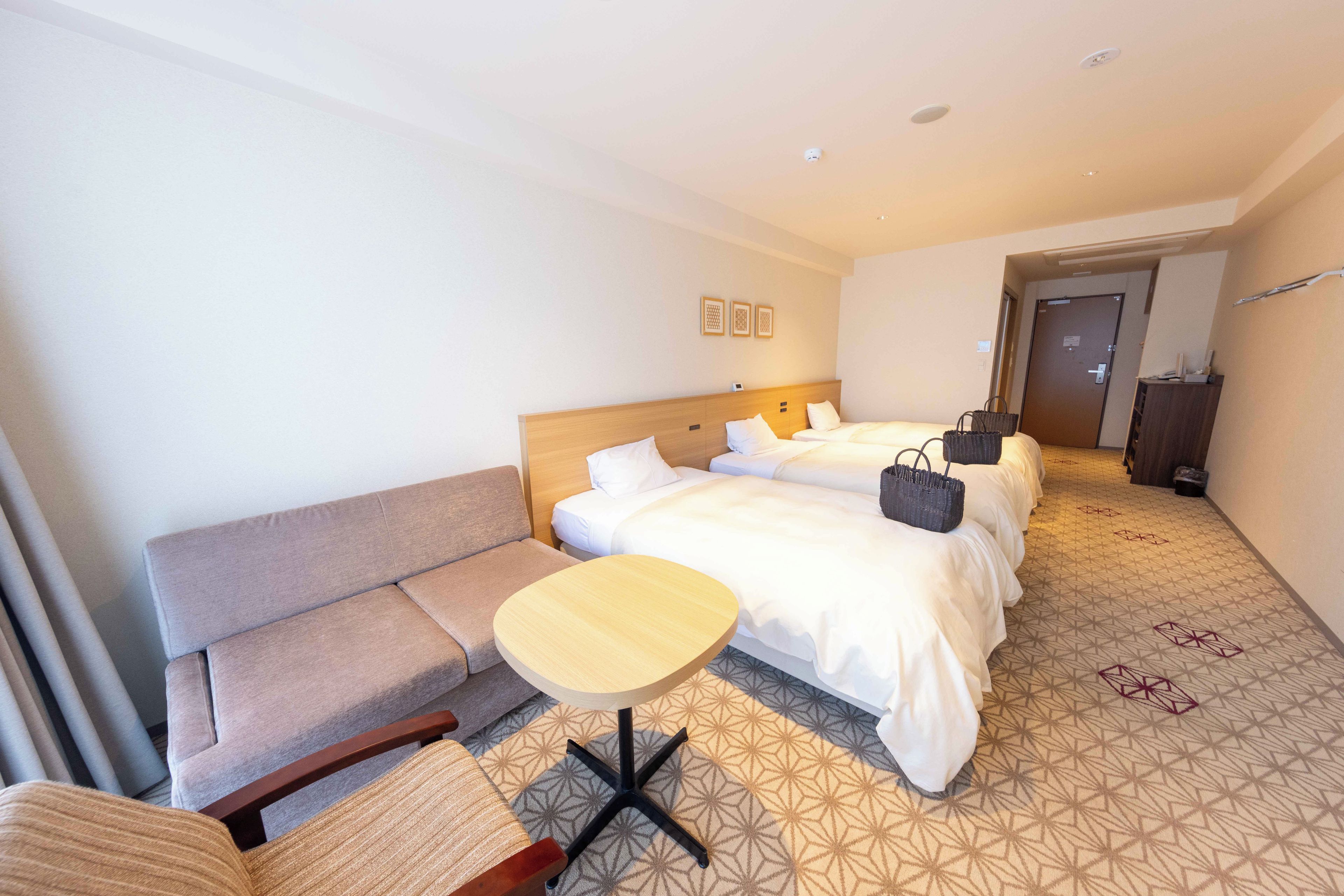 Een hotelkamer met een bed, een slaapbank, een tafeltje en een deur.