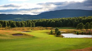 Un parcours de golf doté de bunkers, d’un étang et d’une colline boisée.