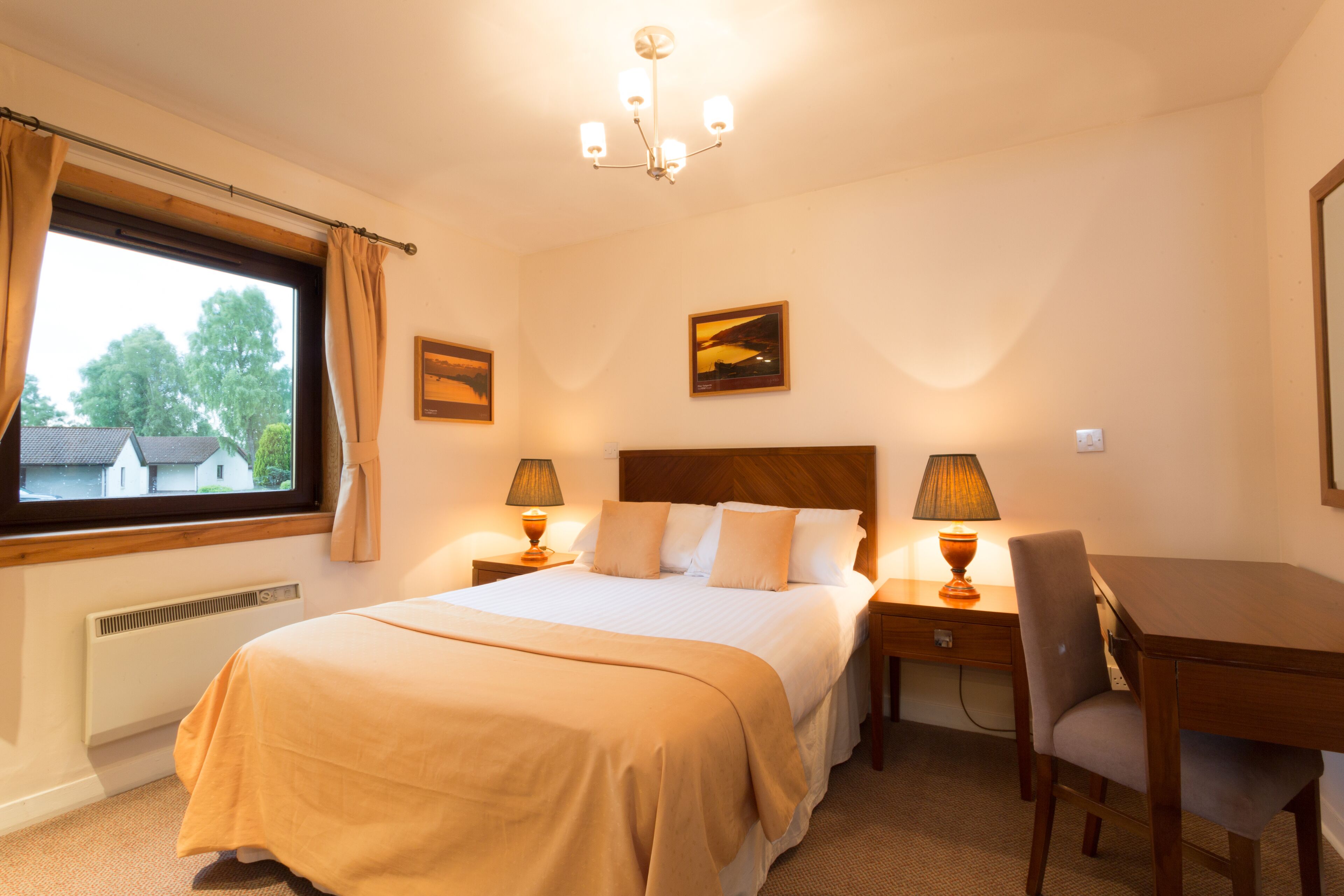 Ein Hotelzimmer mit Bett, Nachttischlampen, Schreibtisch und Stuhl.