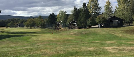 Un parcours de golf avec des bunkers, un drapeau et plusieurs cabanes en bois.