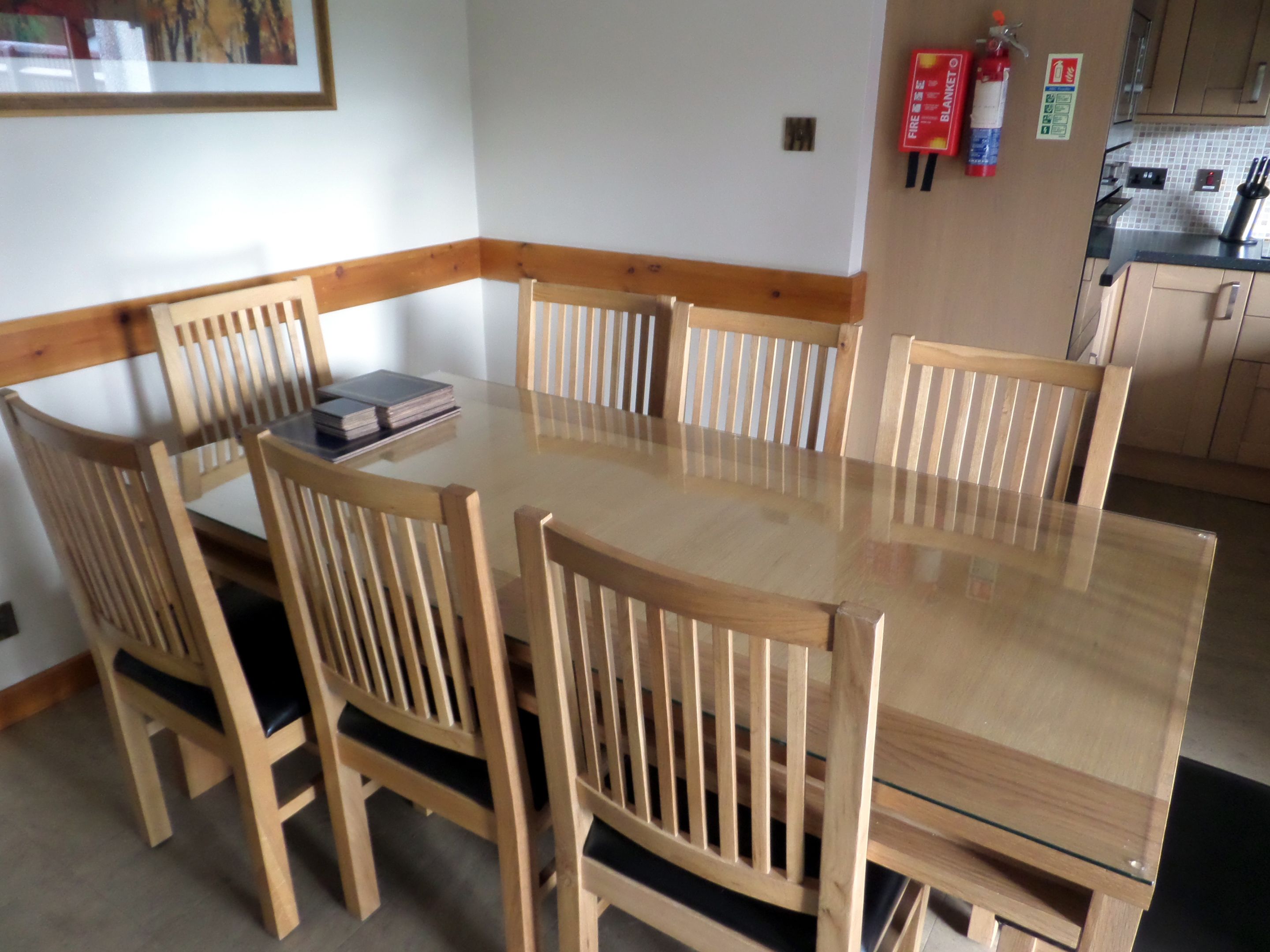 A dining area with a glass-top table surrounded by wooden chairs.