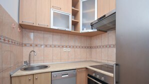 Una cuina amb armaris de fusta, una rentavaixelles d'acer inoxidable, un forn i un frigorífic.
