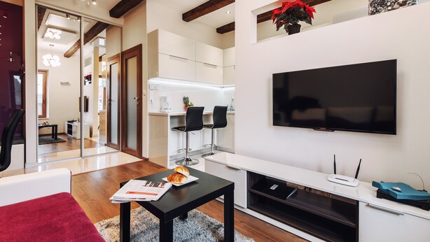 A modern living room with a flat-screen TV, a coffee table with a croissant, and a fireplace. - EchoDom 4 Apartments Szlak (Kraków)