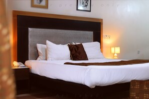 A hotel room with a large bed, a bedside table with a lamp, and a framed picture on the wall.