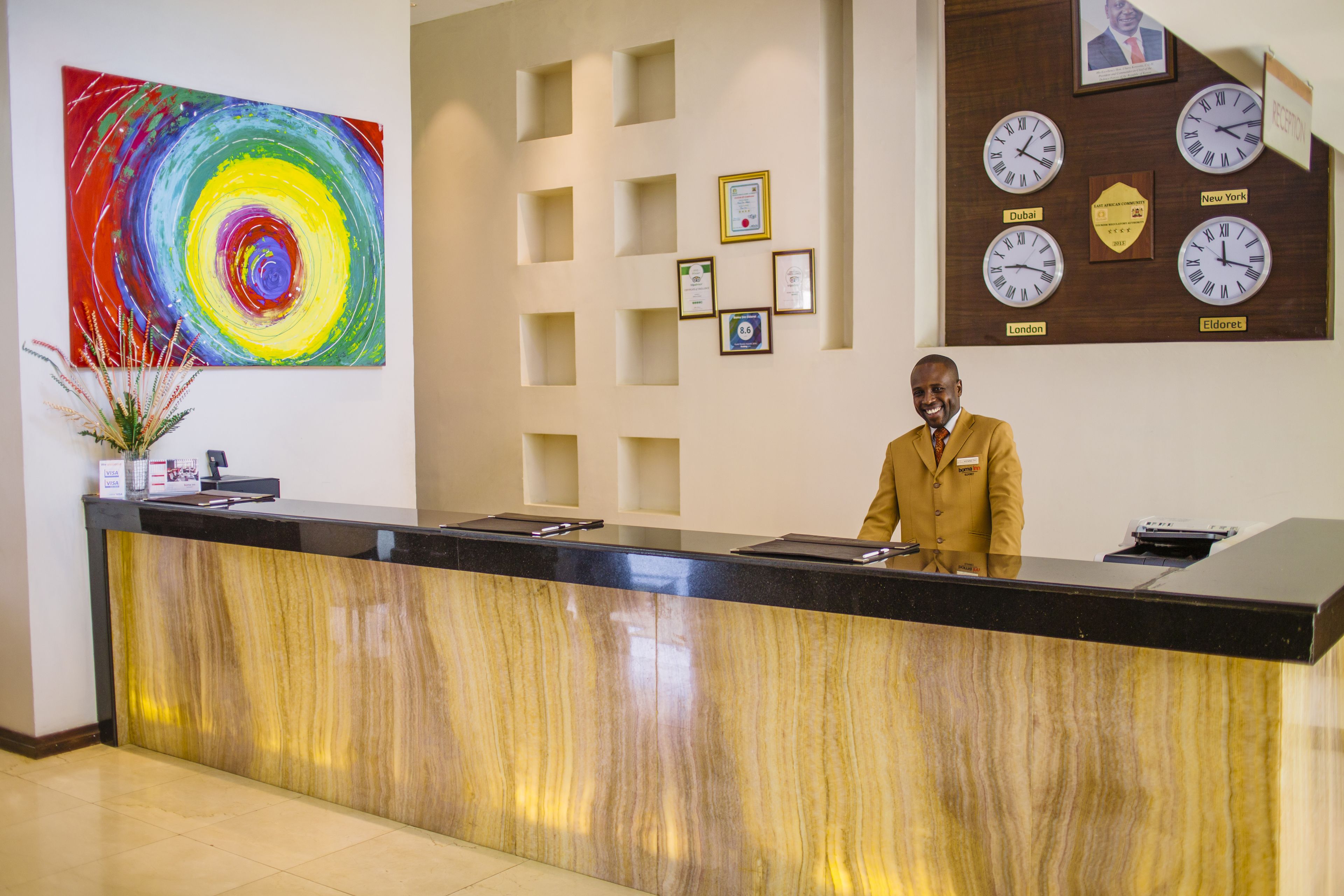 A reception desk with a marble front, a colorful abstract painting, and clocks displaying times from various cities.