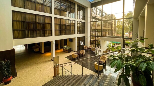 A spacious atrium with a high ceiling, large windows, and a central staircase.