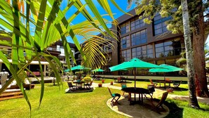 An outdoor patio area with green umbrellas, seating, and a building in the background.