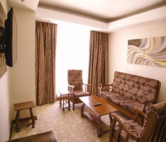 A living room with a sofa, armchairs, a coffee table, and curtains.