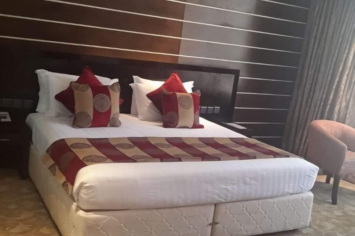 Una cama bien hecha con una colcha estampada, un cabecero y dos almohadas con diseños circulares.