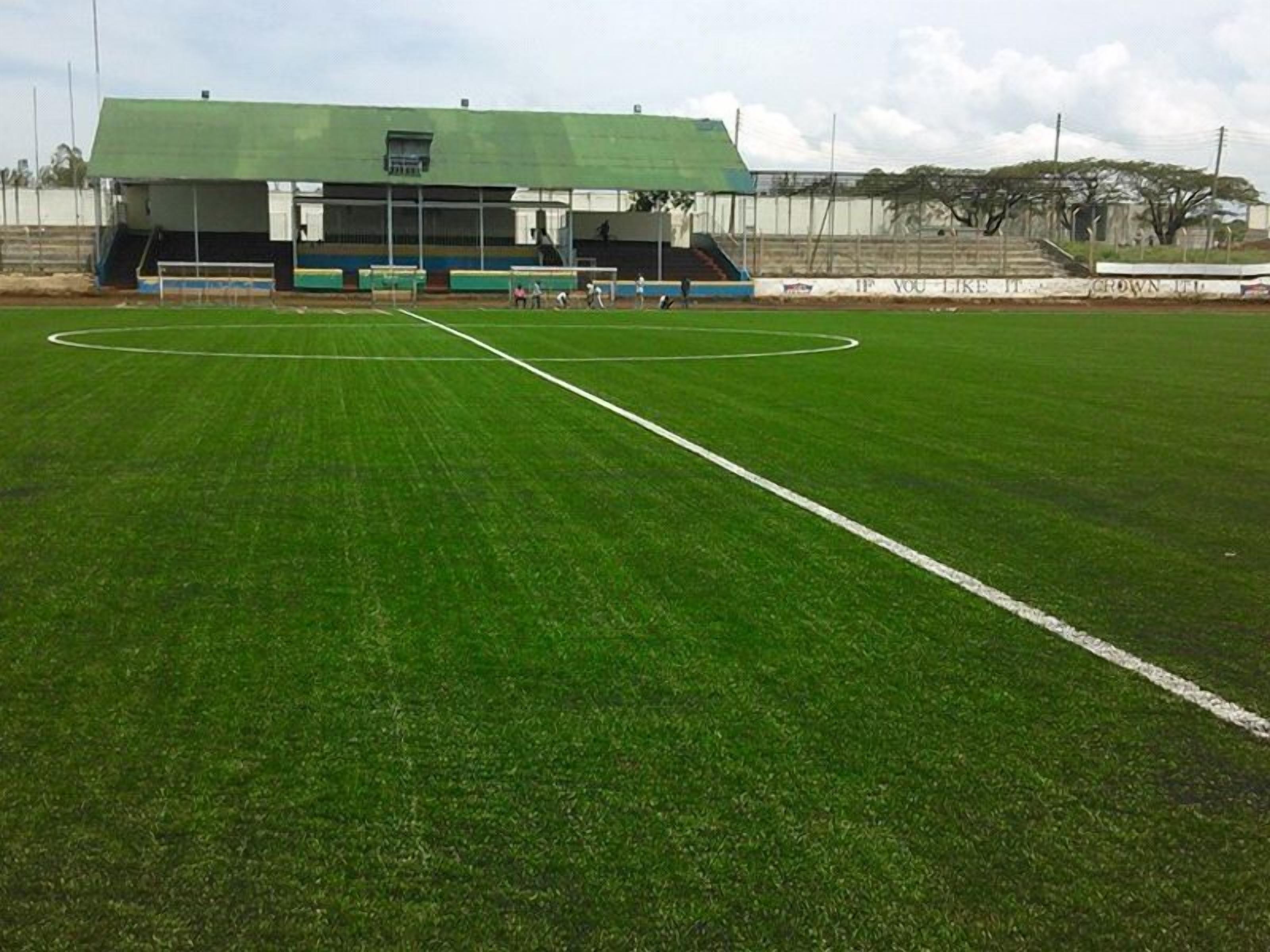 Un campo de fútbol con un edificio de techo verde al fondo.