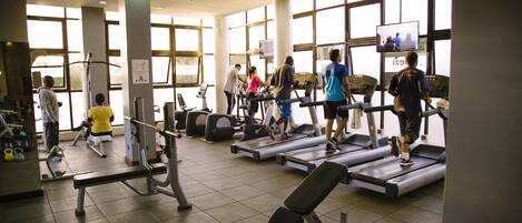 Une salle de sport équipée de tapis de course, d’appareils de musculation et de bancs.