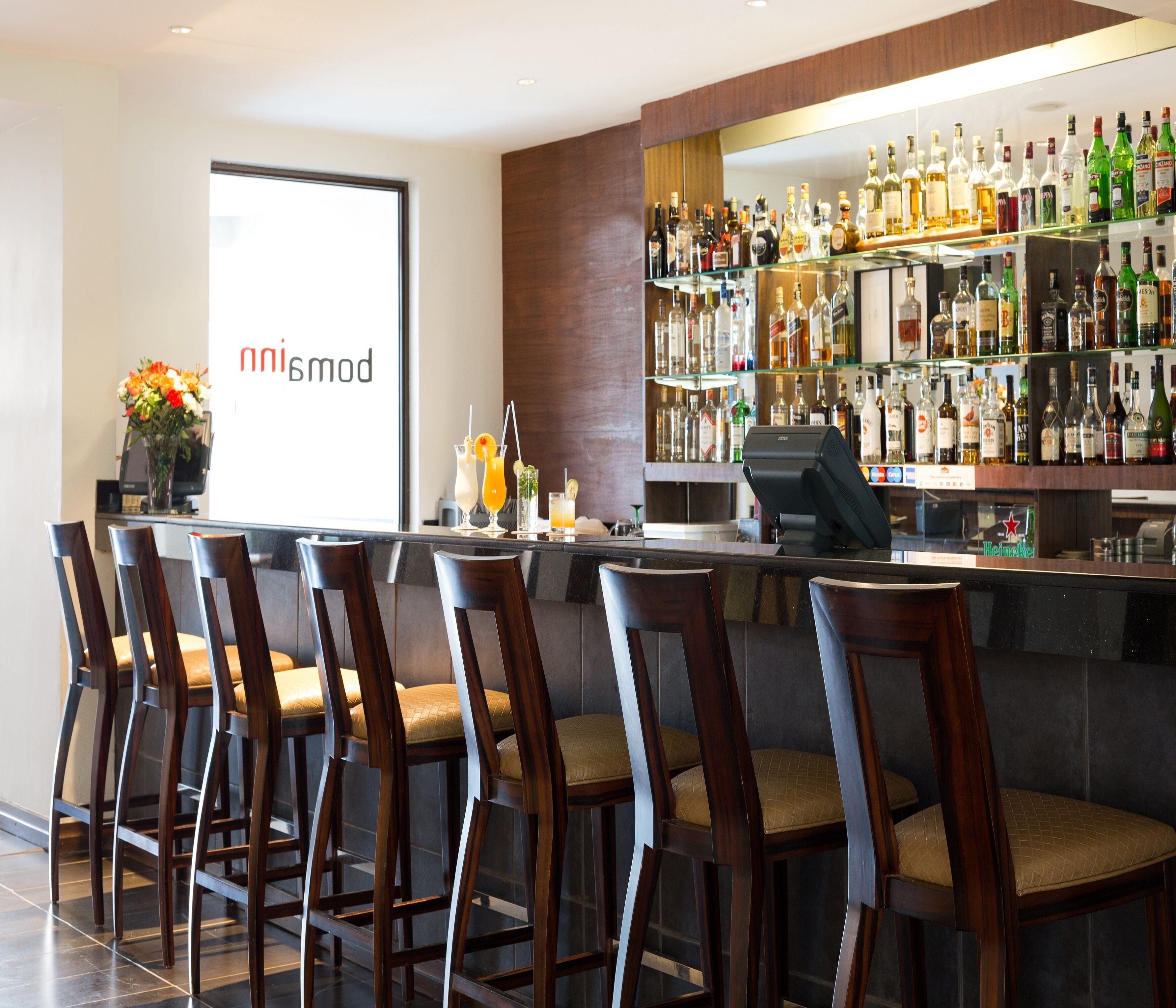 Eine Bar mit mehreren Hockstühlen und einer Auswahl an Spirituosenflaschen.