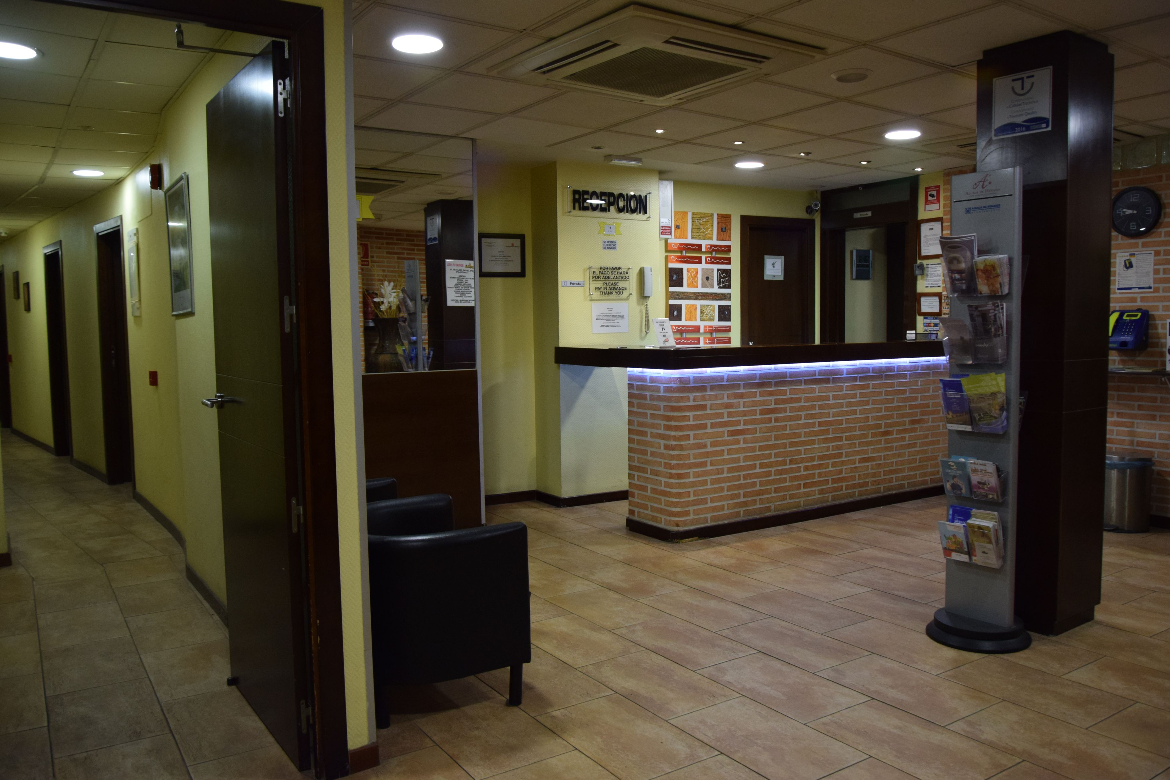 A reception area with a reception desk, chairs, a clock, and a trash can.