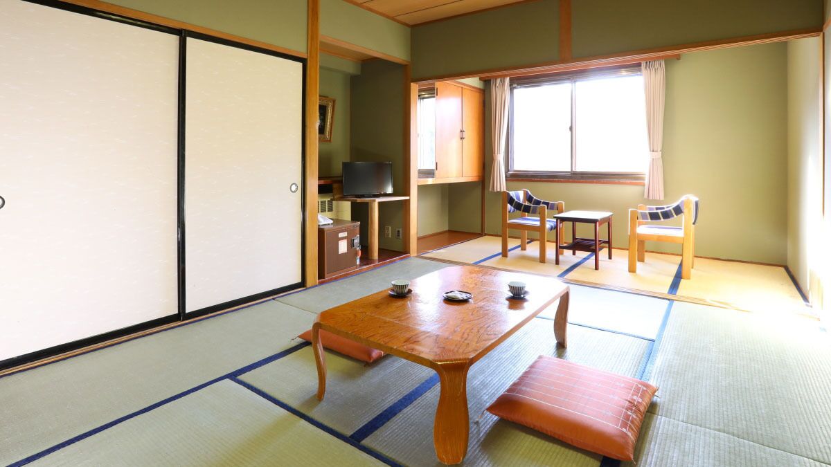 A traditional Japanese room with tatami flooring, a low wooden table, and sliding doors.