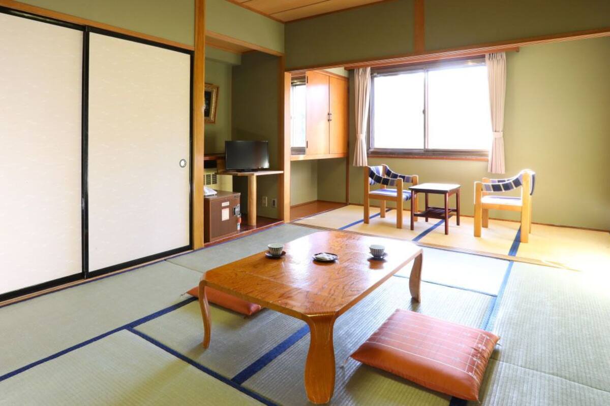 Une pièce de style japonais traditionnel, avec un sol recouvert de tatamis, une basse table en bois et des portes coulissantes.