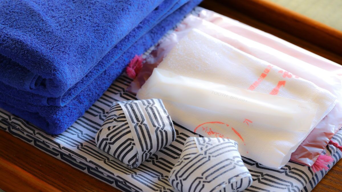 A stack of blue towels, a bar of soap, and a striped cloth on a wooden surface.