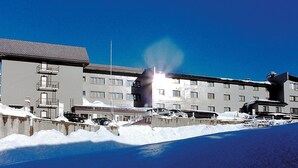 A multi-story hotel with balconies, a parking area, and snow on the ground.
