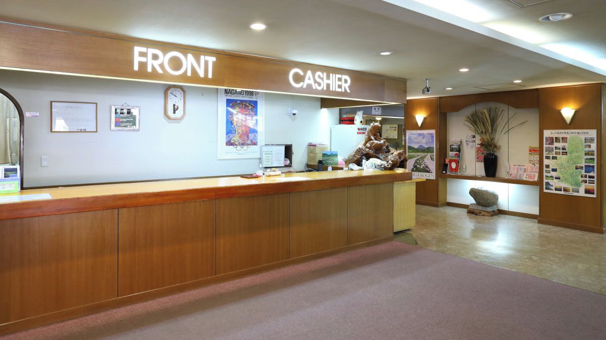A reception desk with a wooden counter, a clock, and a sign indicating 'FRONT' and 'CASHIER'.