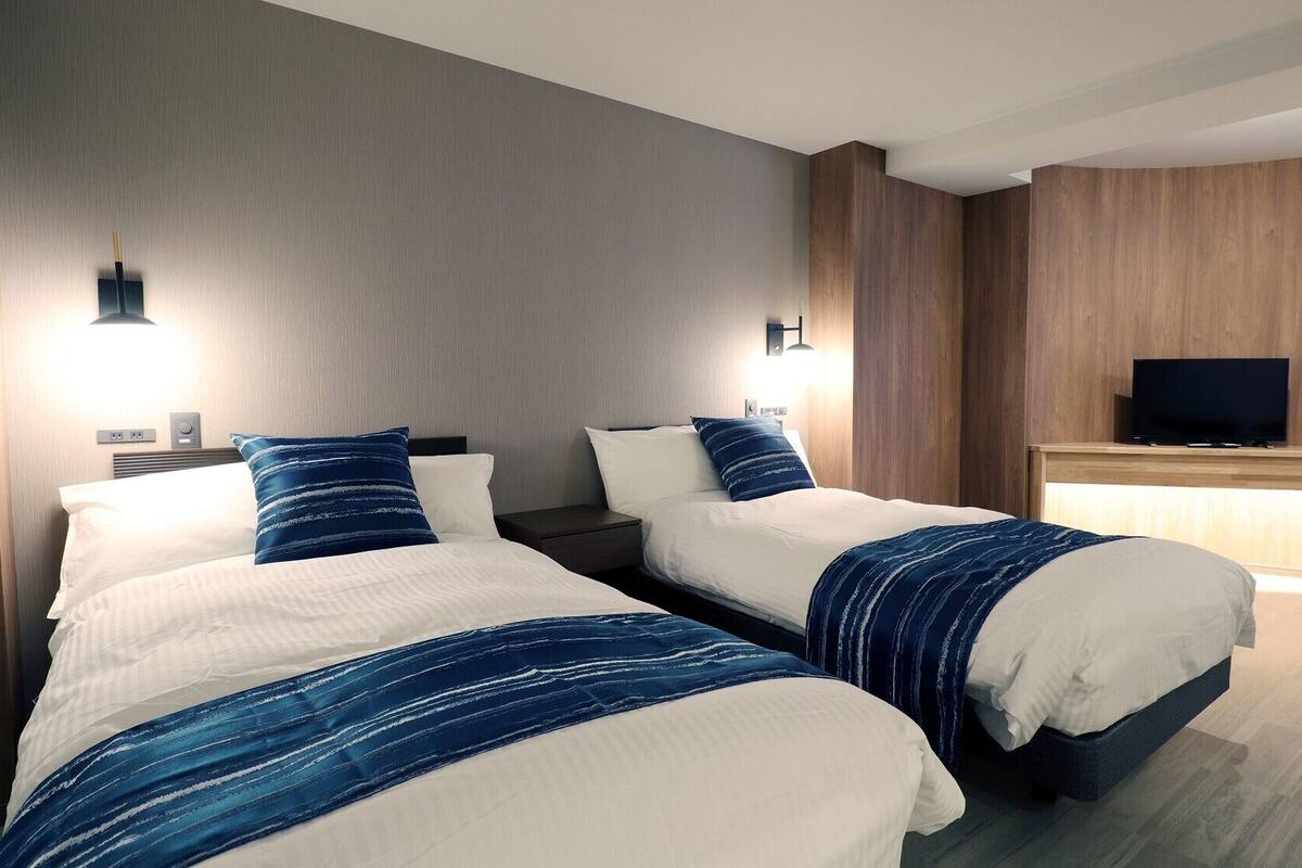 Une chambre d’hôtel avec deux lits, une télévision et un bureau.