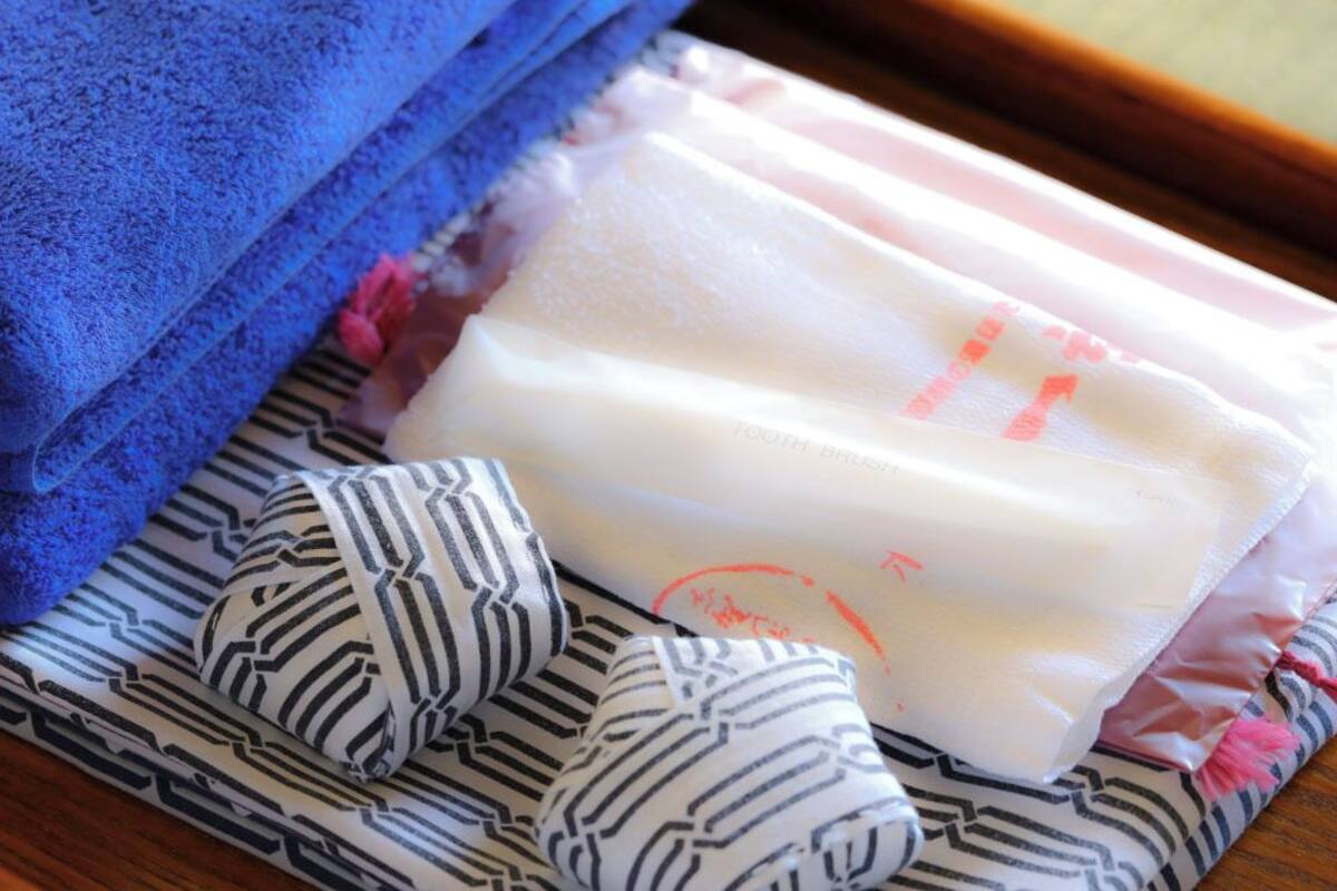 Une pile de serviettes bleues, un savon et des peignoirs rayés posés sur un tissu à motifs.