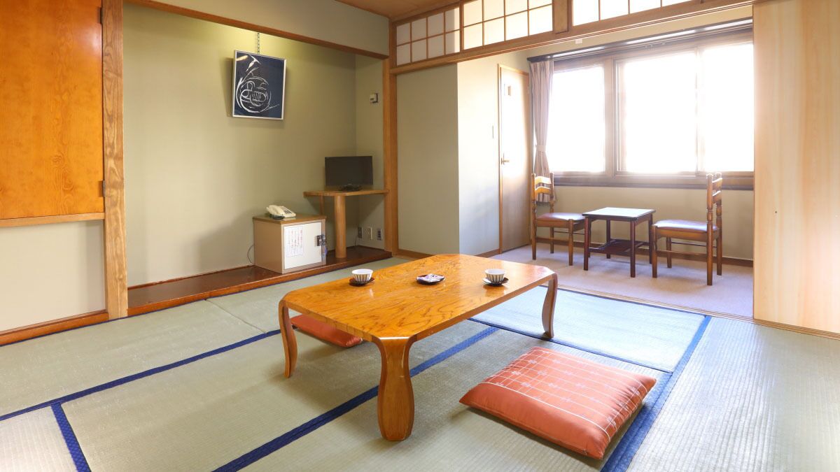A traditional Japanese room with tatami flooring, a wooden table, and a television.