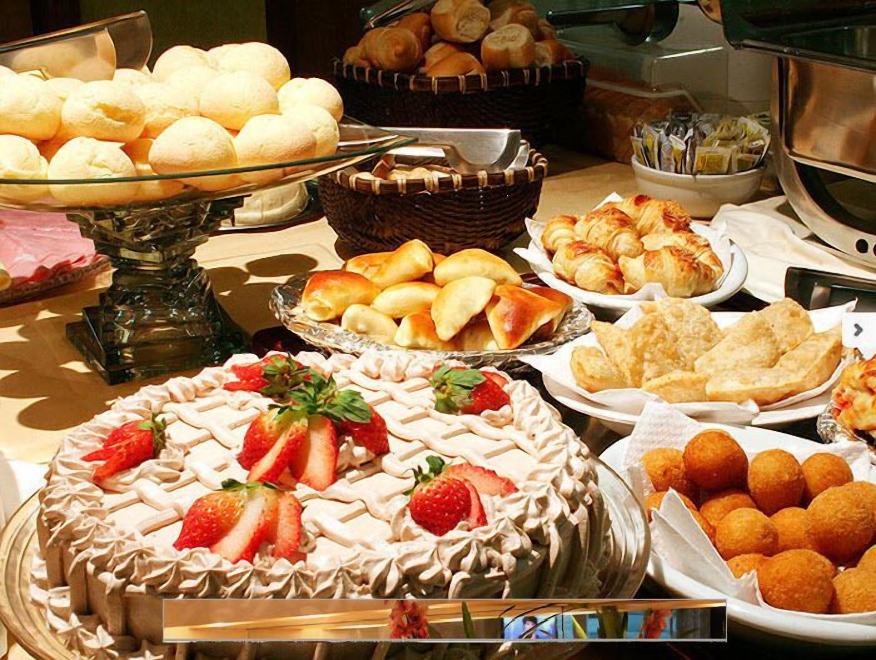 A buffet with various baked goods, including bread rolls, pastries, and a cake with strawberries.