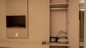 A hotel room with a flat-screen TV mounted on the wall, a minibar, and a small desk area.