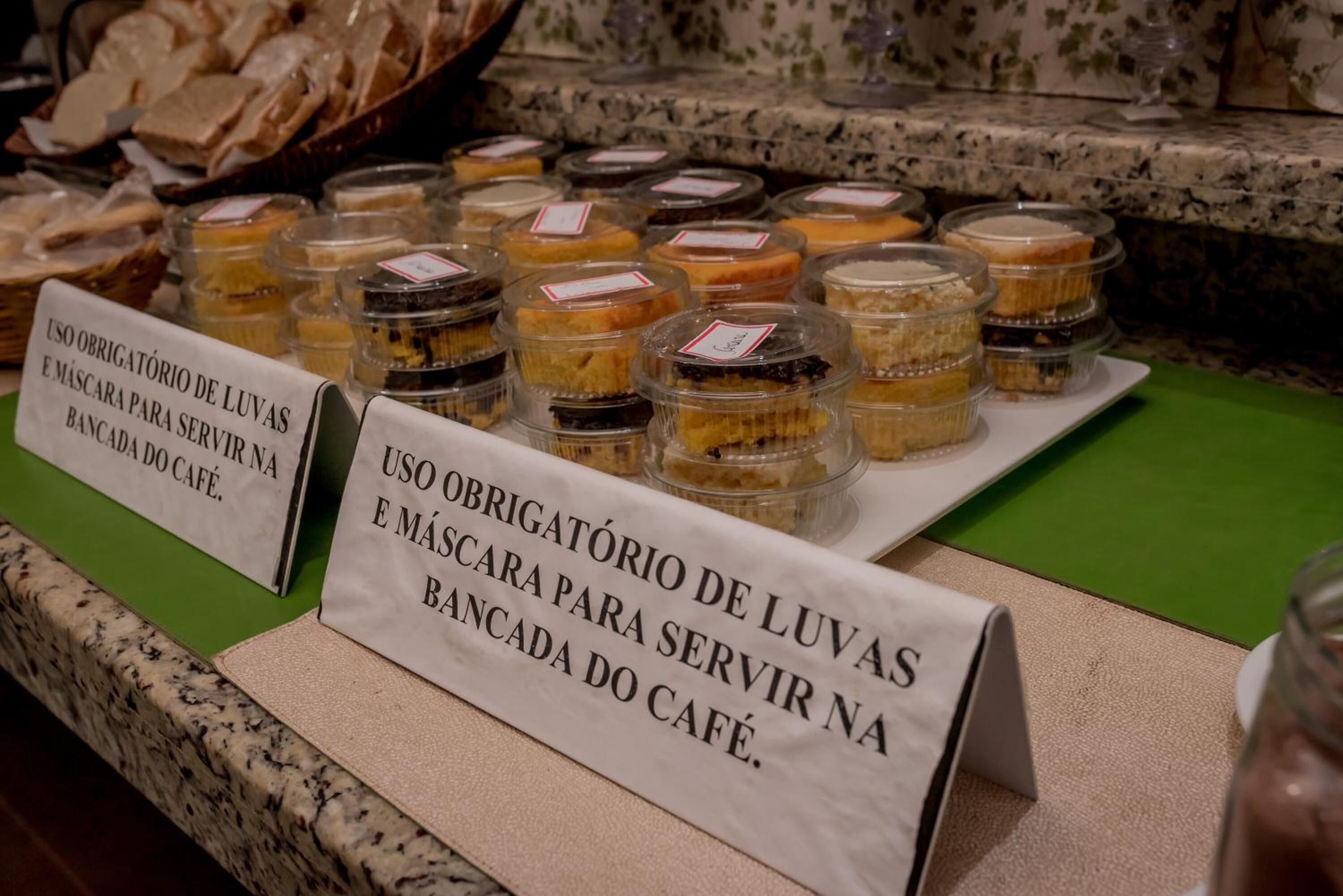 A display of various desserts in clear containers with labels, accompanied by signs indicating the use of plastic for serving and storage.