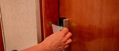 Una mano che usa una carta per sbloccare una porta dotata di una serratura elettronica moderna.