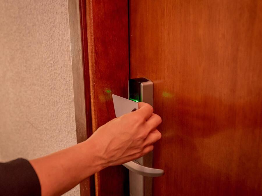 Una mano usando una tarjeta para abrir una puerta con una cerradura electrónica moderna.