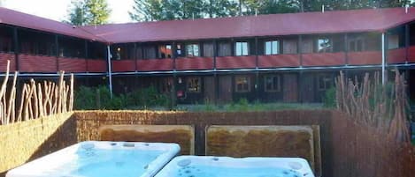 Un edificio con techo rojo y varias ventanas. En la parte delantera, hay dos jacuzzis.