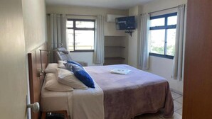 A hotel room with a bed, a TV, and two windows with curtains. - Ameris Hotel Vila Rica Flat (Resende)