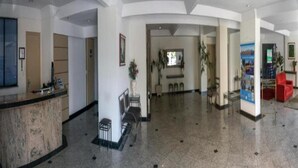 A spacious lobby with a reception desk, seating area, and a large poster on the wall. - Ameris Hotel Vila Rica Flat (Resende)