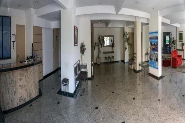 A spacious lobby with a reception desk, seating area, and a large poster on the wall.