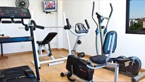 A home gym with an elliptical, a stationary bike, and a treadmill. - Ameris Hotel Vila Rica Flat (Resende)