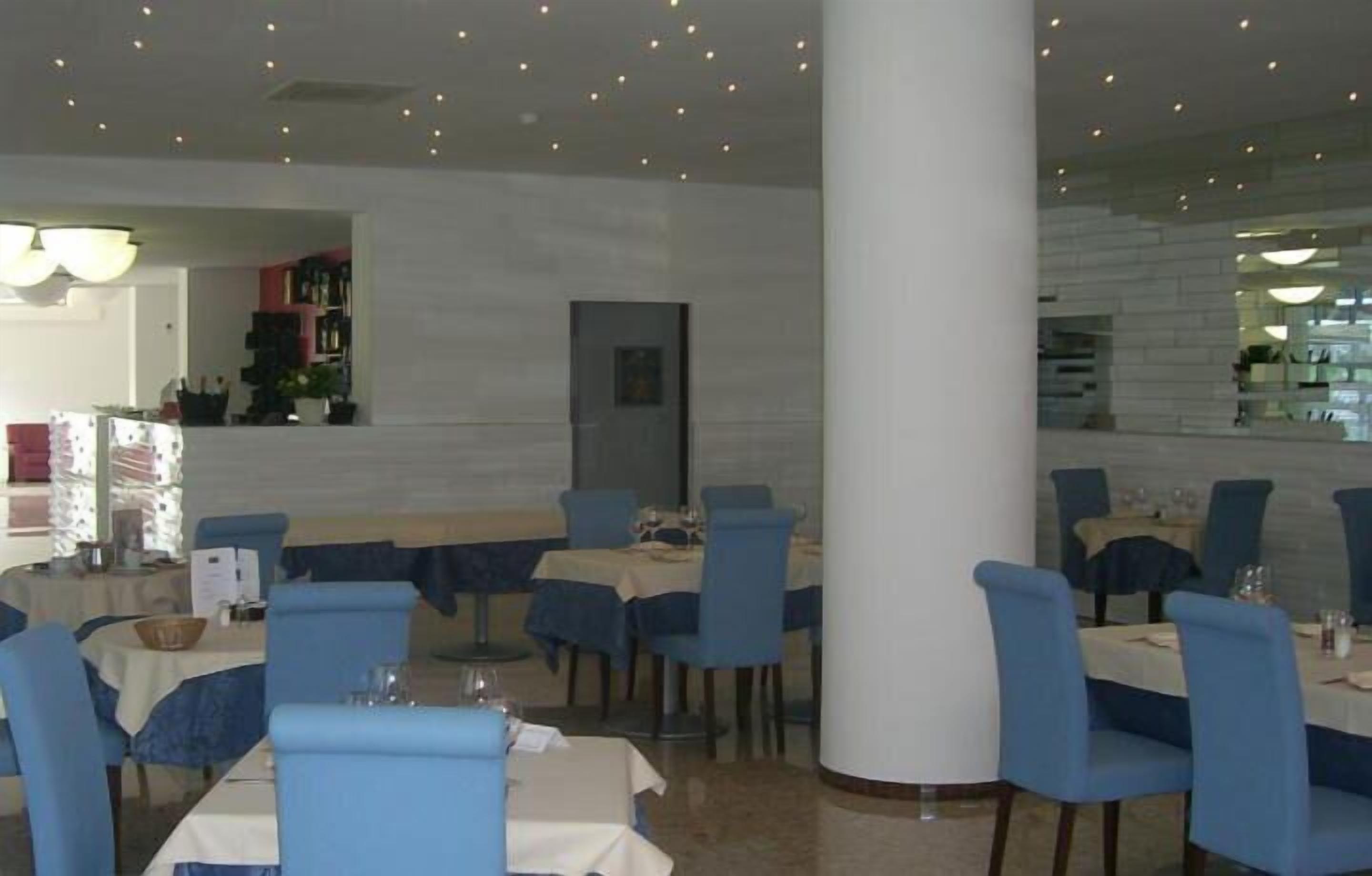 En restaurant med lyseblå polstrede stole, hvide dugge og en central søjle.