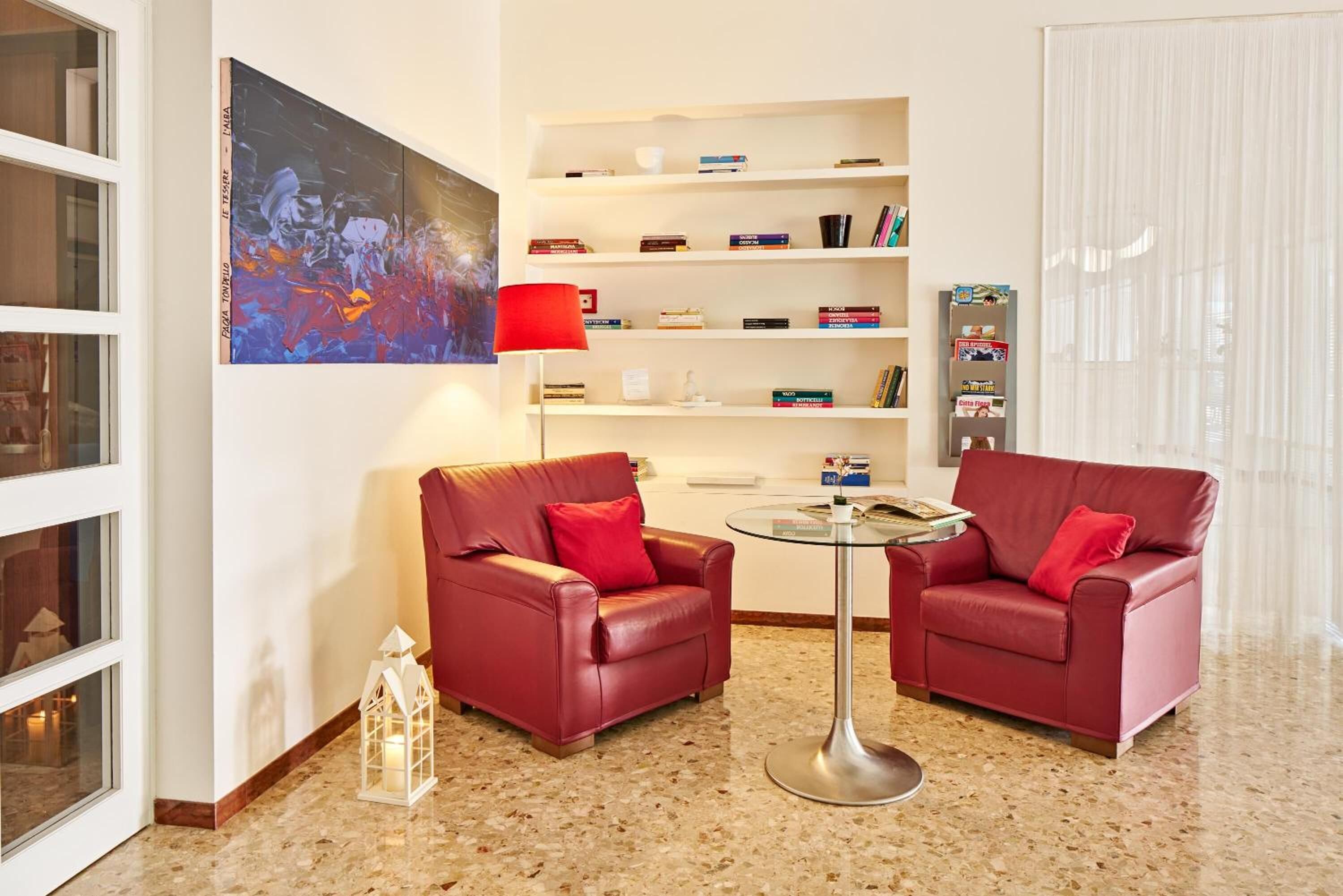 Ein modernes Wohnzimmer mit zwei Ledersofas, einem Glastisch und einem Bücherregal voller Bücher und Dekoration.