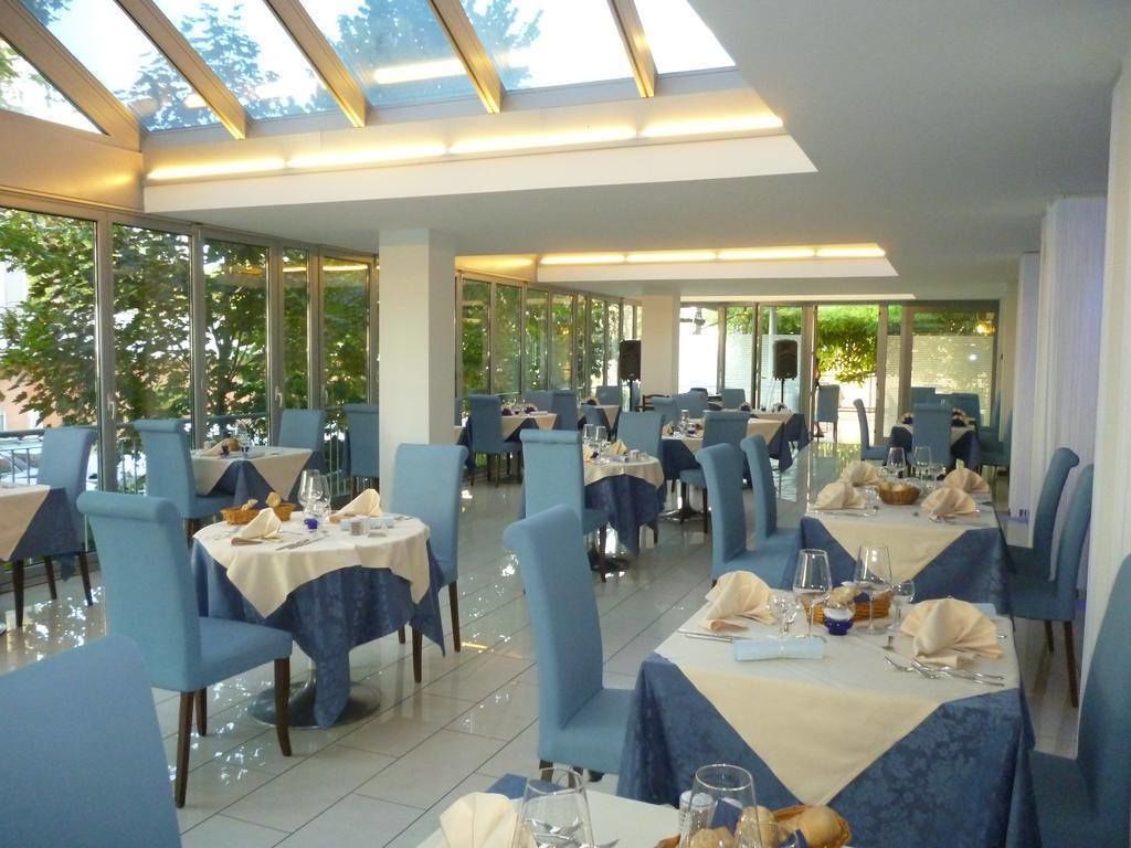 A restaurant with multiple tables and chairs, large windows, and a skylight.