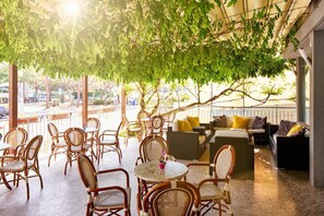 An outdoor seating area with wicker furniture and a view of the street. - Hotel Europa (Grado)