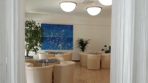 A modern lounge area with round seating and a large abstract painting on the wall. - Hotel Europa (Grado)