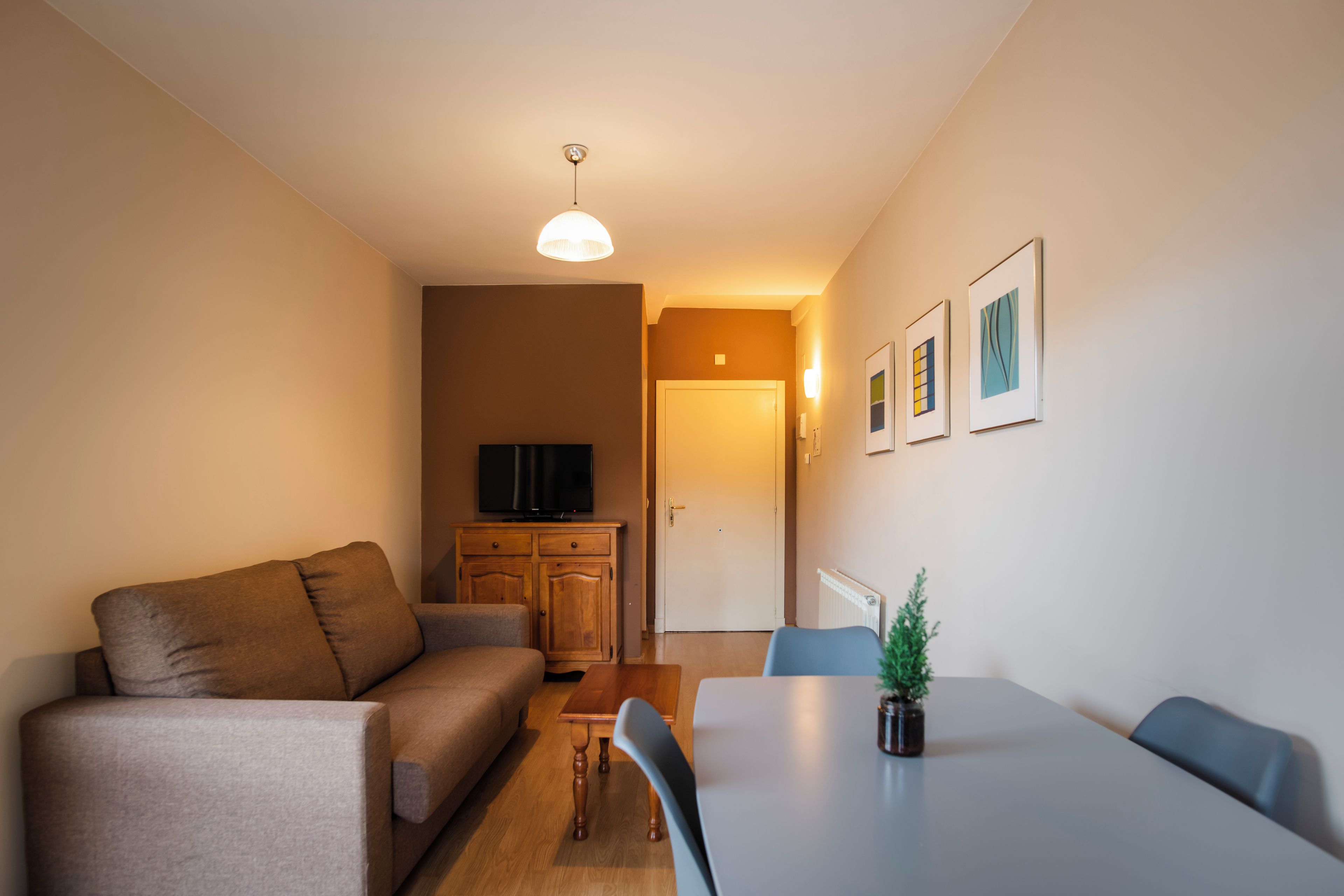 Una sala de estar moderna con un sofá, una mesa de comedor y un televisor.