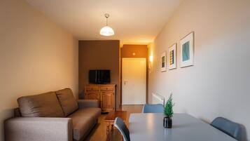 Una sala de estar moderna con un sofá, una mesa de comedor y un televisor.