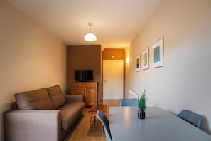 A modern living room with a sofa, a dining table, and a TV.