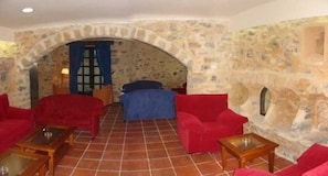 A room with a stone wall, red sofas, a blue sofa, and a small table.