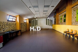 A spacious hallway with a high ceiling, stone walls, and a seating area with chairs. - Ligueerre Resort (Abizanda)