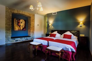 Une chambre avec un grand lit, deux tables de chevet, une commode, un banc en bois, un mur en pierre et un tableau.