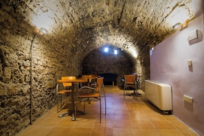 A stone-walled interior with tables and chairs, a radiator, and a small table lamp. - Ligueerre Resort (Abizanda)