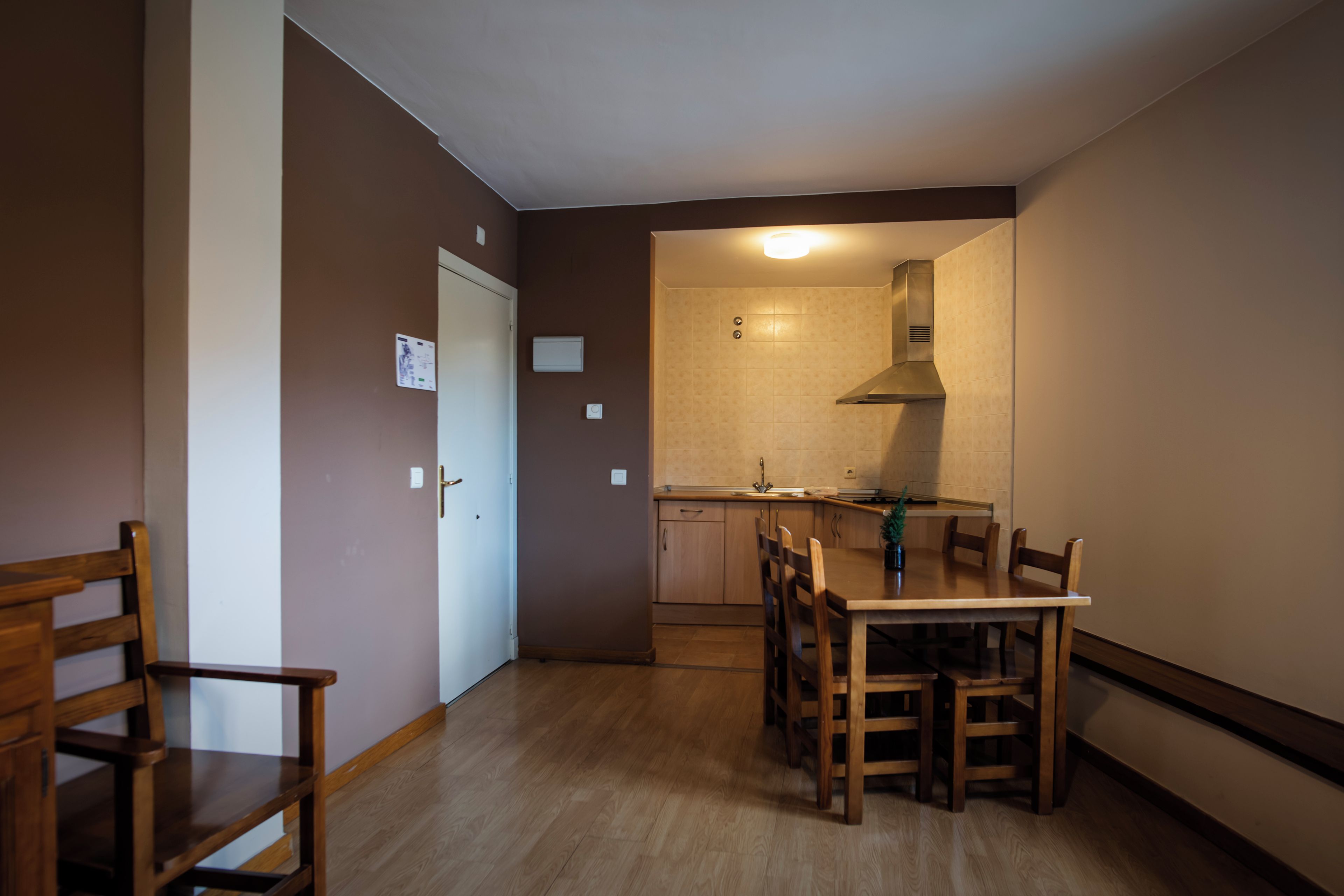 A compact kitchen with a dining area, wooden furniture, and a modern stove.